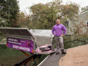 Matt Smith, owner of Roof Monster, standing on a residential roof in Clifton Park, NY next to an Equipter 4000 debris management trailer.